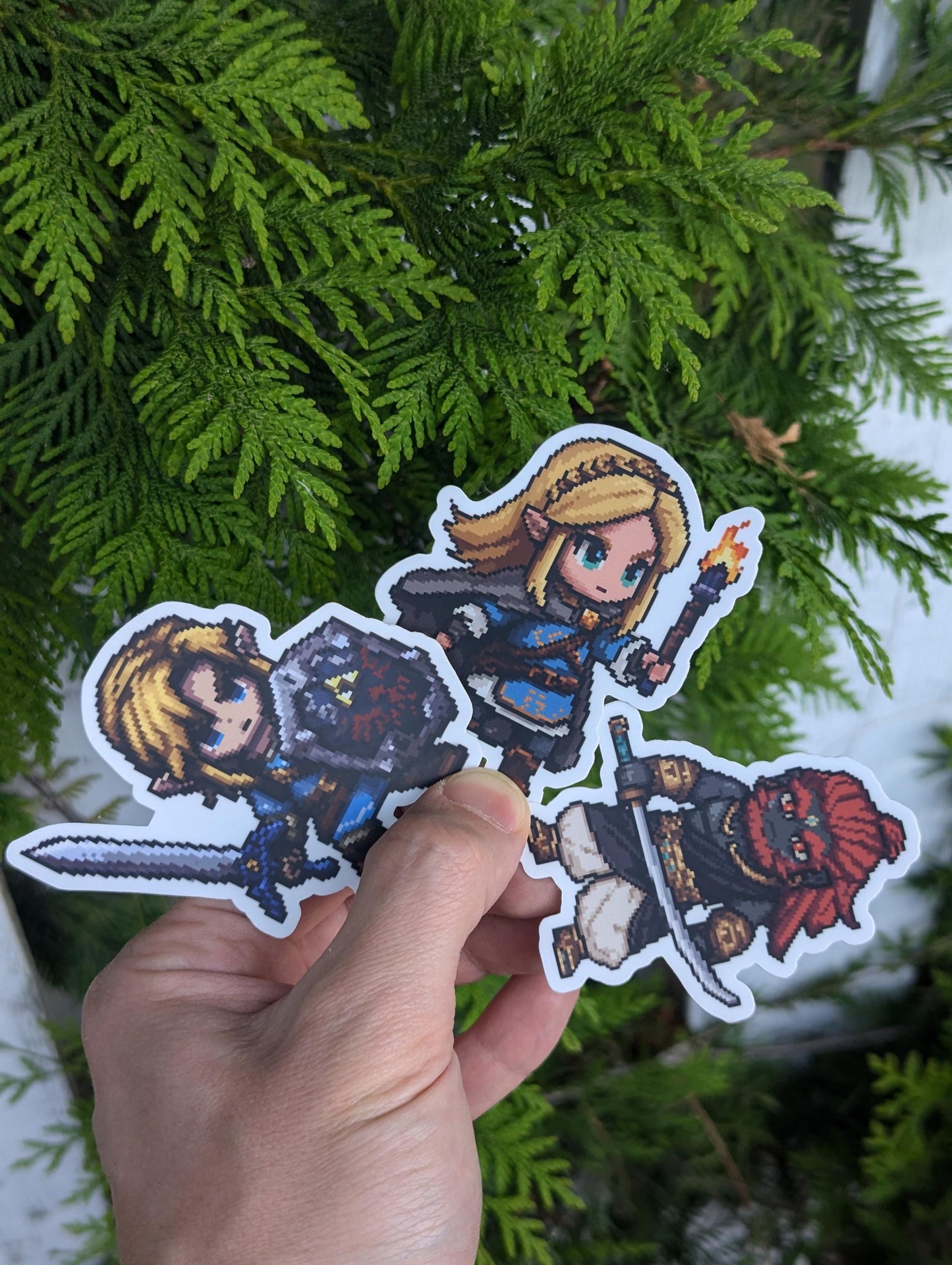 Composite chibi pixel-art sticker featuring Ganondorf, Link, and Zelda from The Legend of Zelda: Tears of the Kingdom, each in signature pose with their weapons.