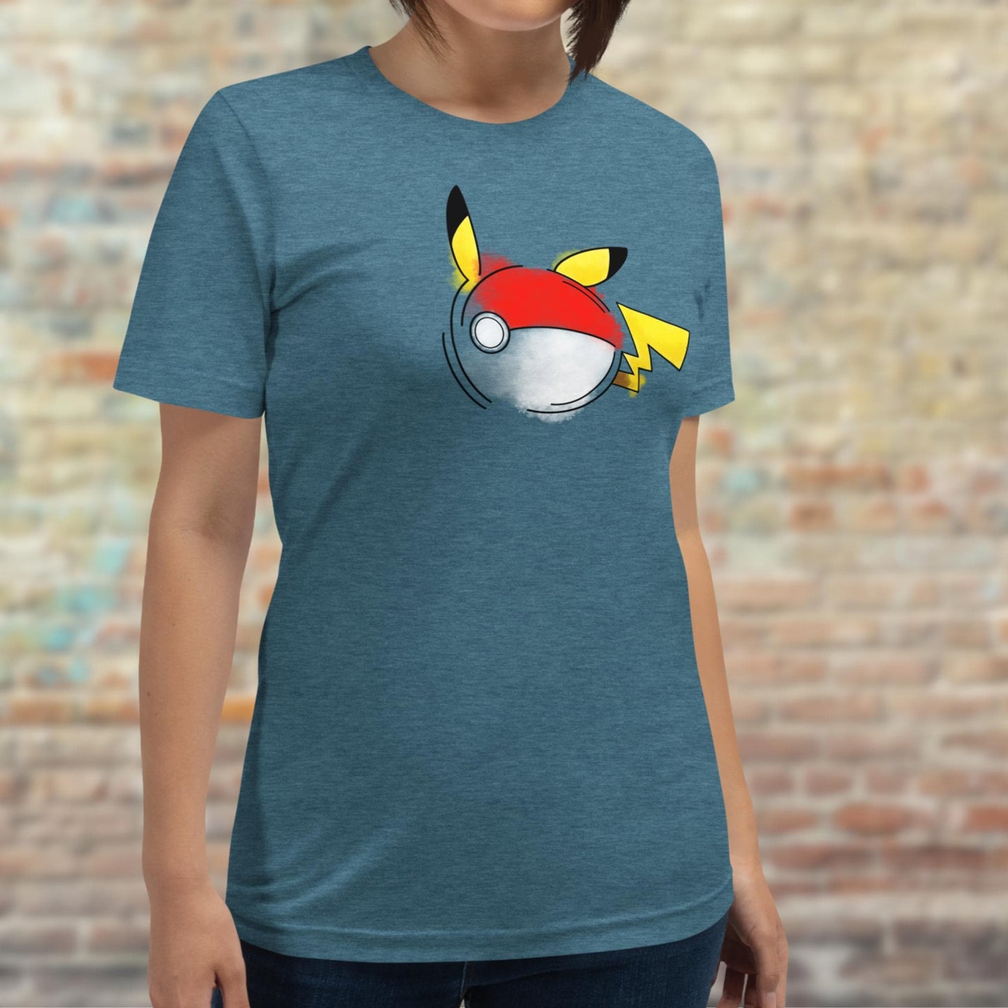 T-Shirt featuring a Pokemon fan art inspiration of Pikachu morphed with a Pokeball. The Signature red Pokeball is shown with Pikachu's noticeable yellow ears with black tips and the zig zaggy tail. The design is intricately painted in a watercolor style with vibrant colors.