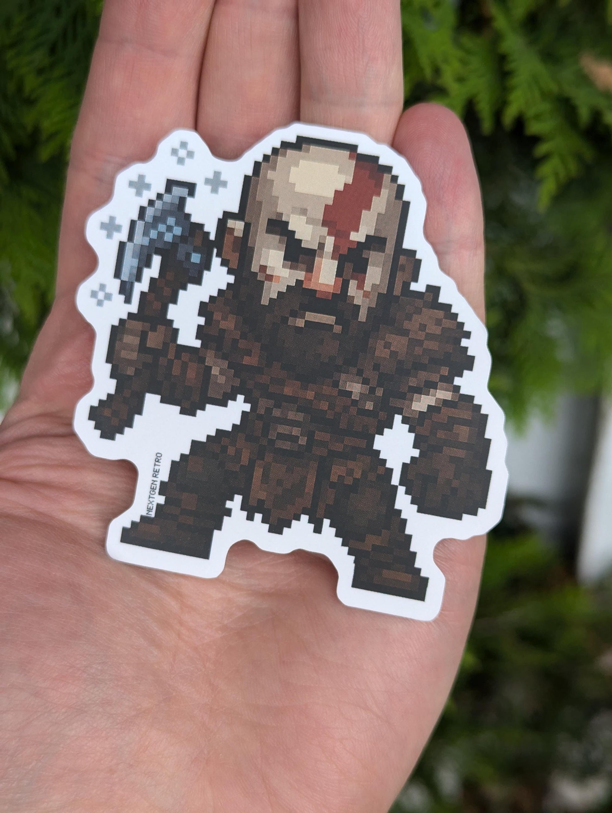 Sticker inspired by God of War. Pixelized version of Kratos from Norse era games (God of War and God of War Ragnarok). Norse-era Kratos is wearing his brown armor and holding his axe with snowflakes etched around.