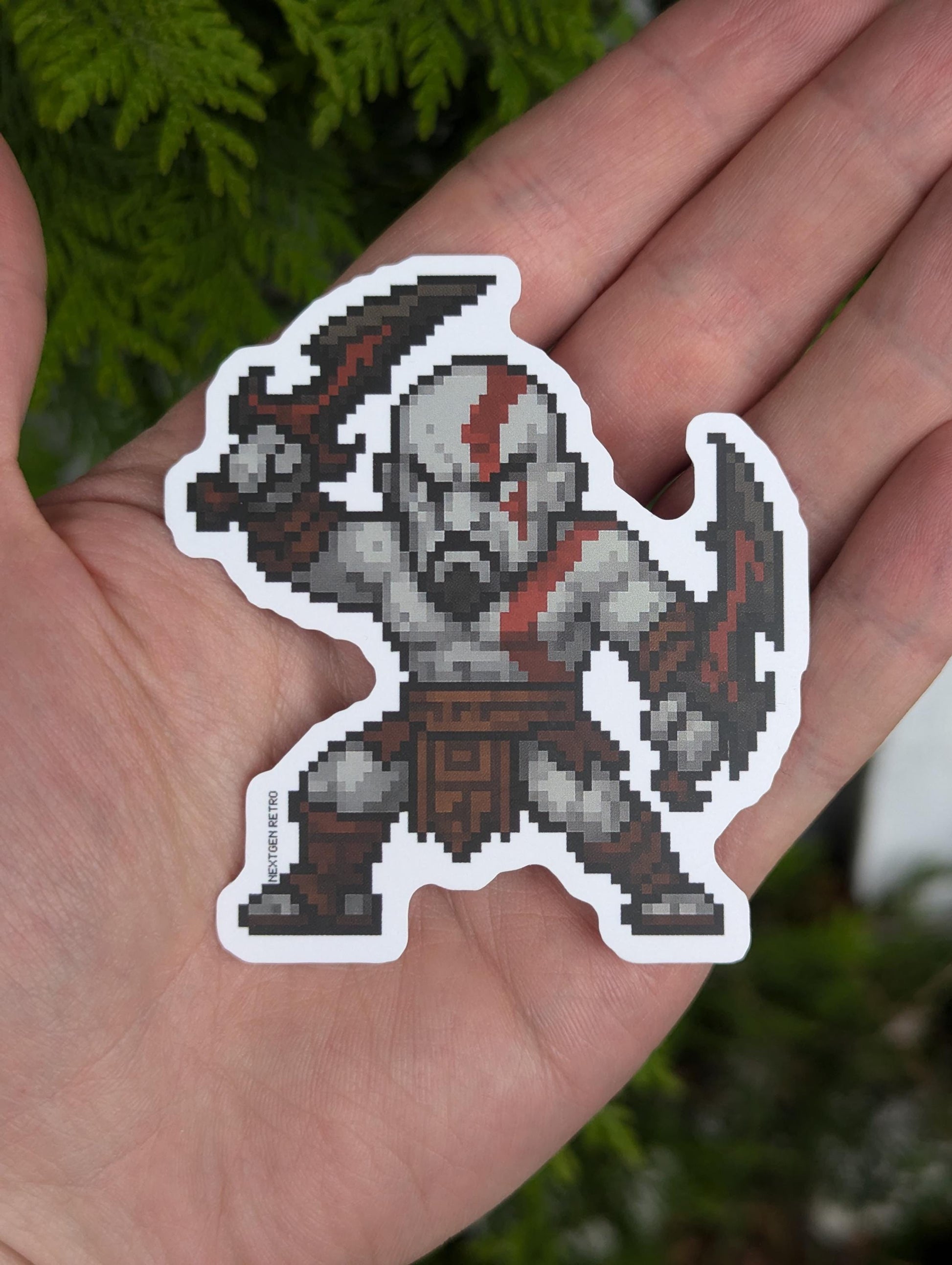Stickers inspired by God of War. Pixelized version of Kratos from Greek era games. Greek era Kratos is pale-skinned, bare-chested and holding up the blades of chaos in both hands.
