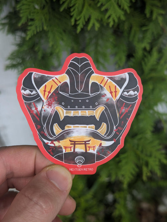 Vinyl sticker with a red outline. Features a samurai mask inspired by the video game Ghost of Tsushima for PlayStation. Primarily black design with yellow filling around the teeth, nose and chin. Red katanas and torii gates are delicately placed on the design.